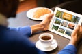 Black Man Using Online Travel Agency Website On Digital Tablet In Cafe Royalty Free Stock Photo