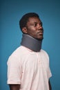 Black man wearing neck brace against blue background minimal Royalty Free Stock Photo