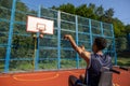 Man in wheelchair, person with disability throwing the ball into the hoop while playing basketball. Royalty Free Stock Photo