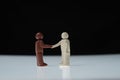 Black man and white man figurines shake hands