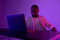 a black man in a white suit works at a computer. evening work in the office