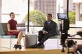 Black man and white woman on TV interview set look to camera Royalty Free Stock Photo