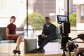 Black man and white woman on TV set, focus on foreground