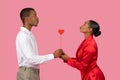 Black man and woman hold heart stick, profile view, love concept, pink background Royalty Free Stock Photo