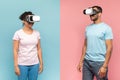 Black man and woman in VR headset experiencing virtual reality, standing over halved pink and blue background Royalty Free Stock Photo