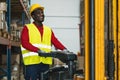Black man working in warehouse with forklift loading delivery boxes