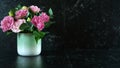 Black marble counter with vase of pink lisianthus flowers with copy space.