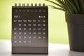 Black March 2021 calendar with green backgrounds and potted plant