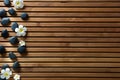 Black massage pebbles and spa flowers set on wooden board Royalty Free Stock Photo