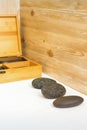 Black massage stones lying near the wooden box with massage rocks on the towel on the table. Royalty Free Stock Photo