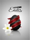 Black mat realistic egg with metallic floral pattern diagonal wrapped red ribbon. Gray background reflection and white narcissus