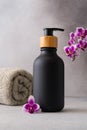 A black matte bottle and rolled grey towel and a vibrant purple orchid flower accentuate the spa-like atmosphere Royalty Free Stock Photo