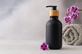 A black matte bottle and rolled grey towel and a vibrant purple orchid flower accentuate the spa-like atmosphere Royalty Free Stock Photo