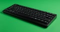 A black mechanical keyboard is placed on a bright green surface. The keyboard Royalty Free Stock Photo