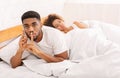 Black man cheater talking privately on cellphone in family bed Royalty Free Stock Photo
