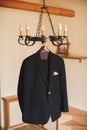 A black men`s suit hangs on a hanger on the chandelier. Royalty Free Stock Photo