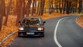 black Mercedes-Benz W126 in autumn forest.