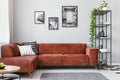 Black metal bookshelf in grey Scandinavian living room interior with brown velvet sofa Royalty Free Stock Photo