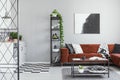 Metal bookshelf in grey Scandinavian living room interior with brown velvet sofa Royalty Free Stock Photo