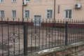 Black metal fence of sharp iron bars in a forged pattern on the street in front of a brown house Royalty Free Stock Photo