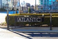 A black metal gate with the word `Atlantic` on the front surrounded by street cones a red curb and black building