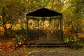 Black metal gazebo and yellowed trees in park