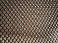 Black metal grating on a background of brown wood surface. Royalty Free Stock Photo