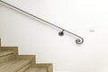 Black metal handrail attached to a white wall on a staircase with wooden steps Royalty Free Stock Photo