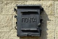 A black metal mailbox hangs on the wall of the house. Russian word: mail