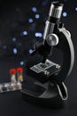black metal microscope on a dark background. test tubes with a red cap Royalty Free Stock Photo