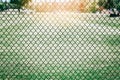 Black metal netting wire mesh fence against green field meadow. Texture pattern surface background Royalty Free Stock Photo