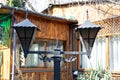 Black metal ornamental lantern near the wooden house at sunny summer day.