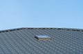 Black metal roof sheets against the blue sky. A modern roof with a skylight Royalty Free Stock Photo