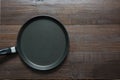 Black metalic skillet for pancakes on wooden board. Top view