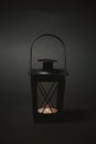 Black metallic portable lantern burning on black background