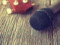 Black microphone on wooden plate with guitar in out of focus ba Royalty Free Stock Photo