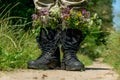 Black military boots with flowers. Concept - flowers instead of bullets and war. Ending the war in Ukraine. The surrender of the Royalty Free Stock Photo