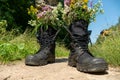 Black military boots with flowers. Concept - flowers instead of bullets and war. Ending the war in Ukraine. The surrender of the Royalty Free Stock Photo