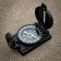 Black military style compass with a hinged lid placed on a textured Royalty Free Stock Photo