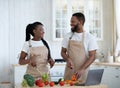 Black Millennial Couple Cooking In Kitchen Together And Using Laptop Computer Royalty Free Stock Photo