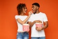 Man and woman eating popcorn on orange background