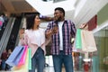 Black millennial couple walking in mall with shopping bags and coffee Royalty Free Stock Photo