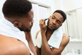 Black millennial guy shaving his beard in bathroom Royalty Free Stock Photo