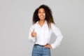Black millennial lady showing thumbs up gesture over gray background Royalty Free Stock Photo