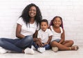 Black millennial mom sitting on floor with daughter and son