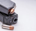 A black 9mm pistol with a loaded magazine on top of it and a single 9mm hollow point bullet next to it Royalty Free Stock Photo