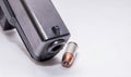 A black 9mm pistol muzzle with a single 9mm hollow point bullet next to it Royalty Free Stock Photo