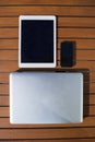 Black mobile phone, tablet, metallic laptop outdoor on an orange wooden table Royalty Free Stock Photo