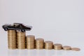 A black model of a car with coins in the form of a histogram on a white background. Concept of lending, savings, insurance