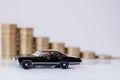 A black model of a car with coins in the form of a histogram on a white background. Concept of lending, savings, insurance